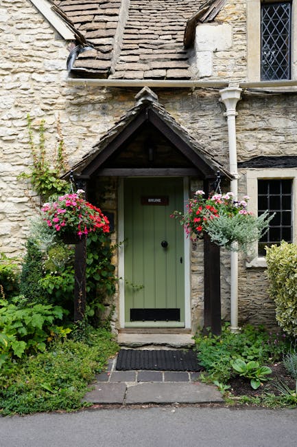 Picturesque stone cottage with a traditional entrance and colorful hanging flowers in rural England.