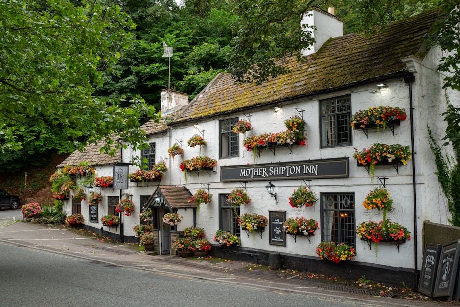Picturesque Mother Shipton Inn adorned with vibrant flowers in Low Bridge, England.